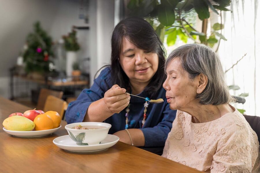 A woman feeding her elderly mother