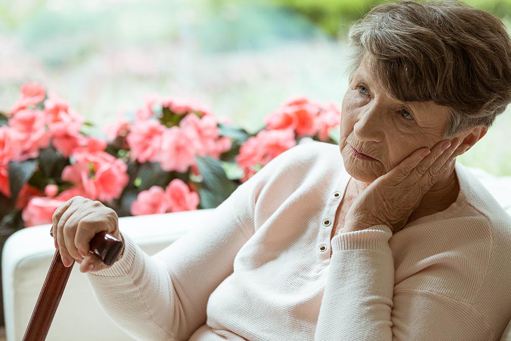 Elderly woman with cane lost in thought