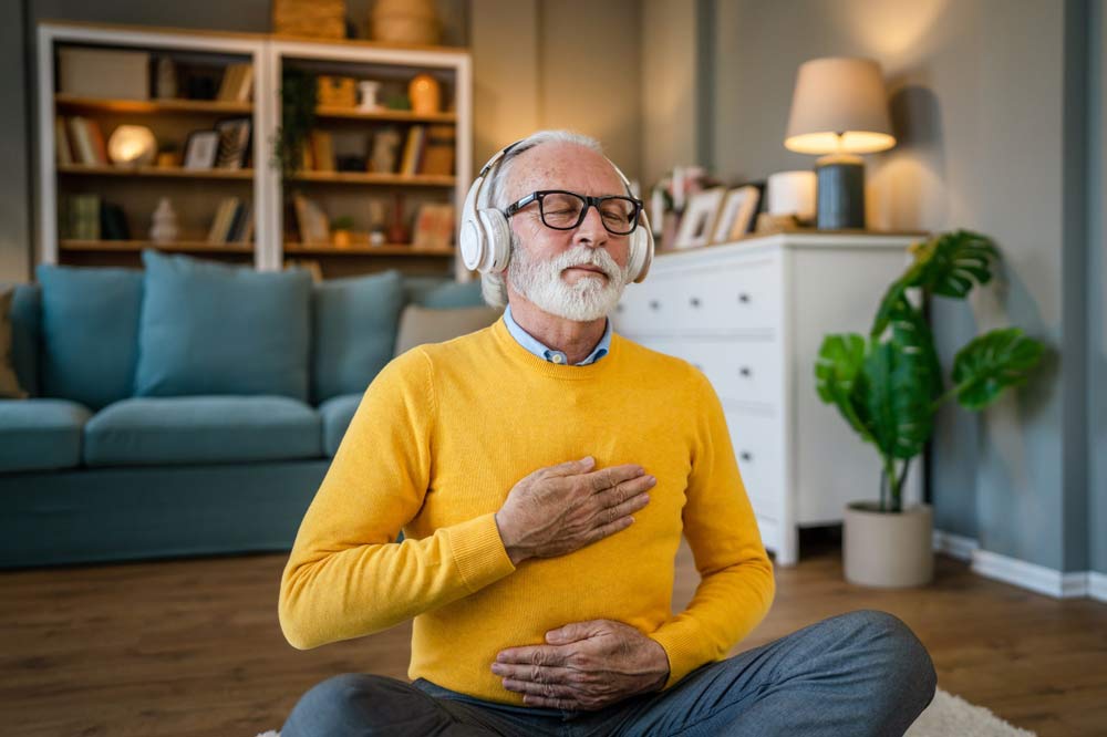 An elderly man sitting on the floor meditating