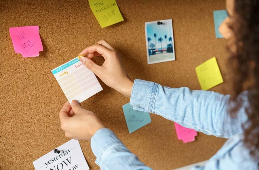 A person posting a planner to a corkboard