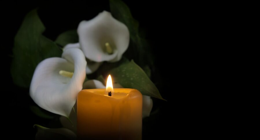 A lit candle surrounded by peaceful white flowers