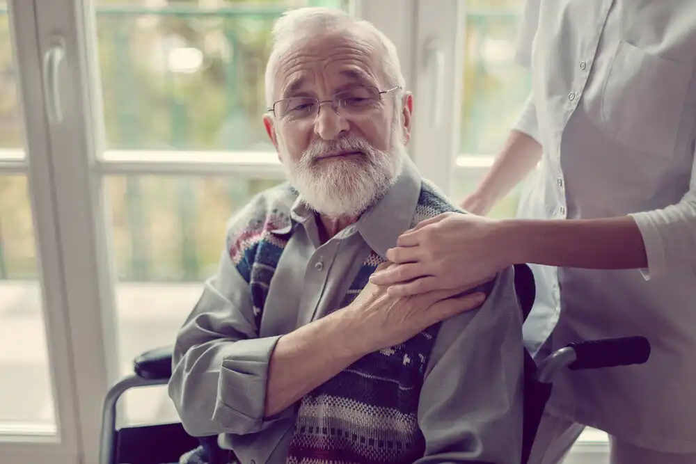An elderly man touching a hospice worker hand on his shoulder