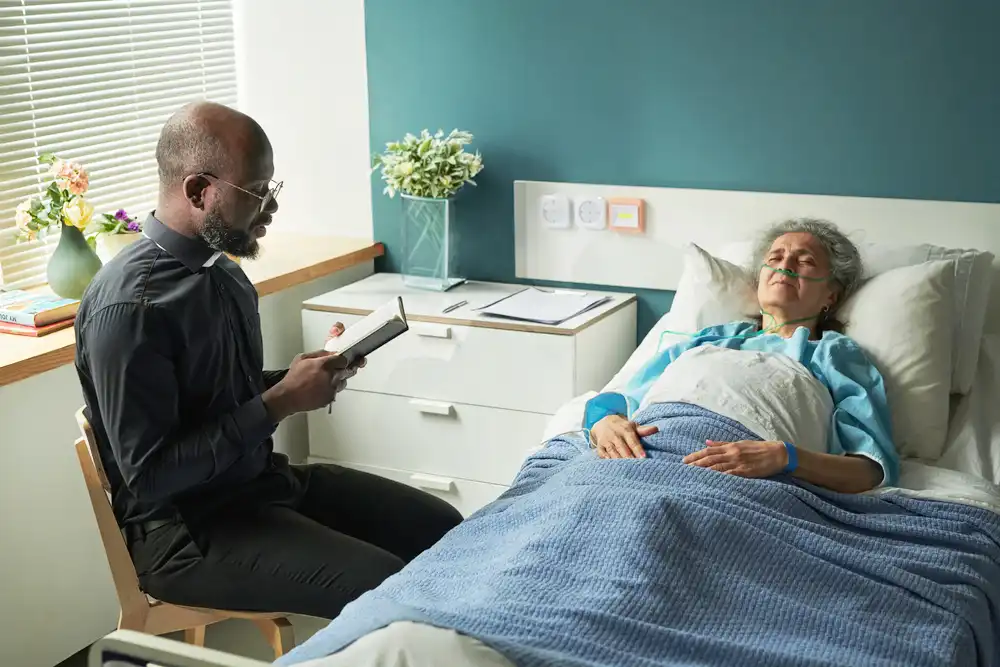 A priest reading to an elderly woman in bed