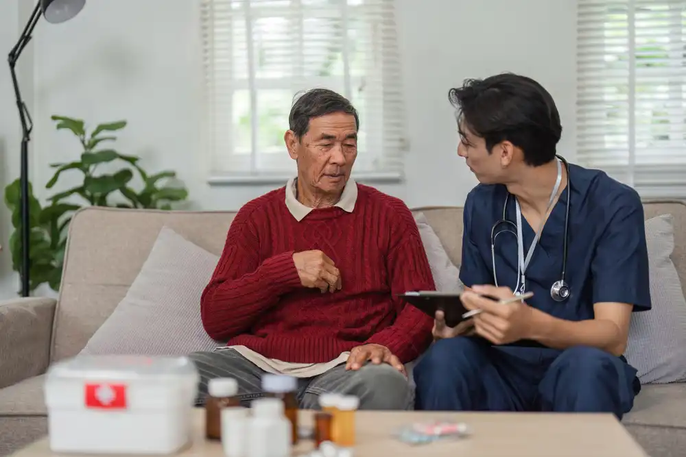 A doctor talking to an elderly man on his couch
