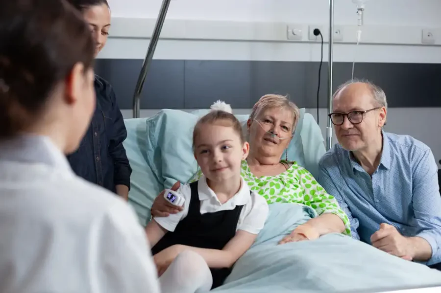 A woman in a hospital bed surrounded by her loving family