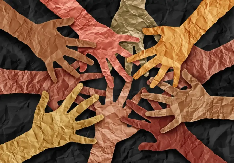 Cutout paper hands stacked on each other in a teamwork huddle