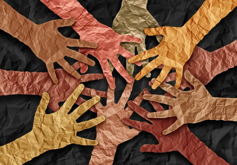 Cutout paper hands stacked on each other in a teamwork huddle