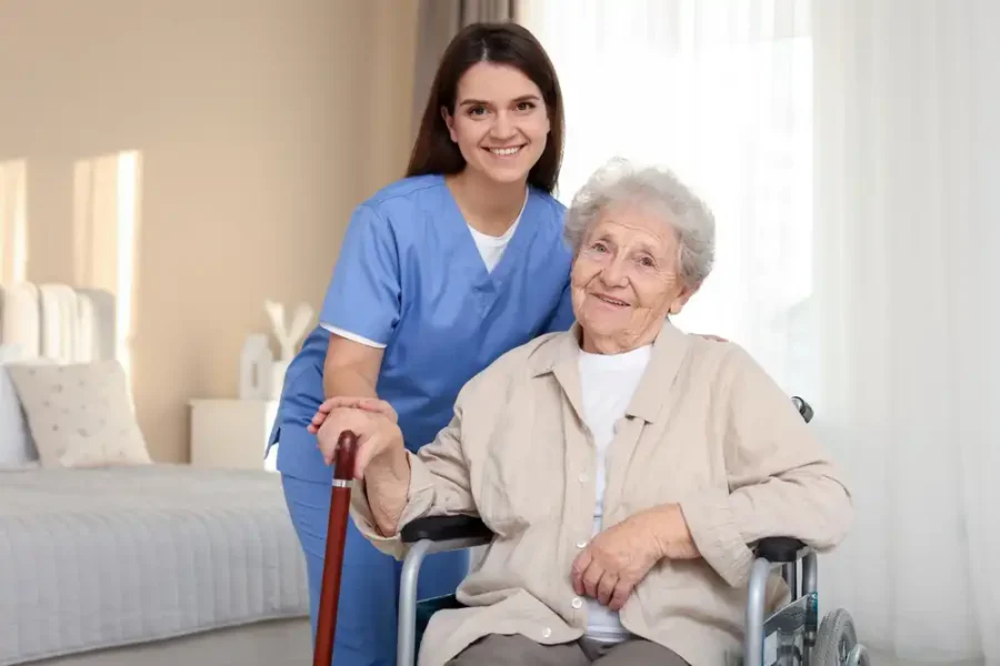 A kind, smiling medical worker with an elderly woman in a wheelchair
