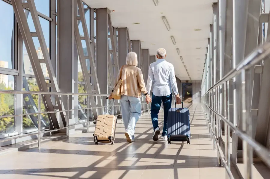 An older couple holding hands walking through a skybridge